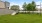 a grassy area with trees and a fence in the background
